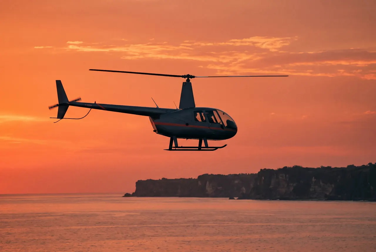 Helicopter silhouette against a coral sunset over the sea off Bali